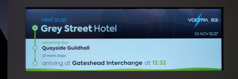 A close up of a TFT next stop display showing a bus route in Gateshead